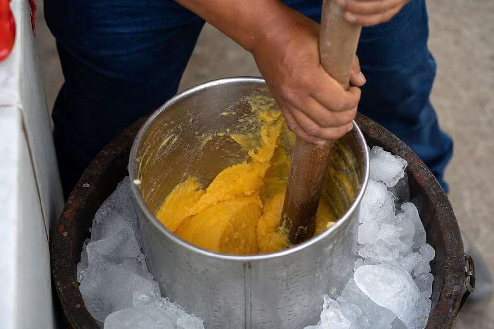 Nieve de garrafa tradicional siendo batida a mano en un barril de madera